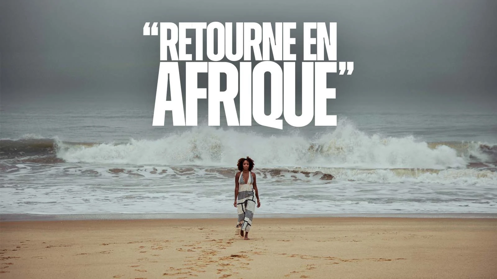« Retourne en Afrique » : une femme marche sur une plage, face à une grande vague.